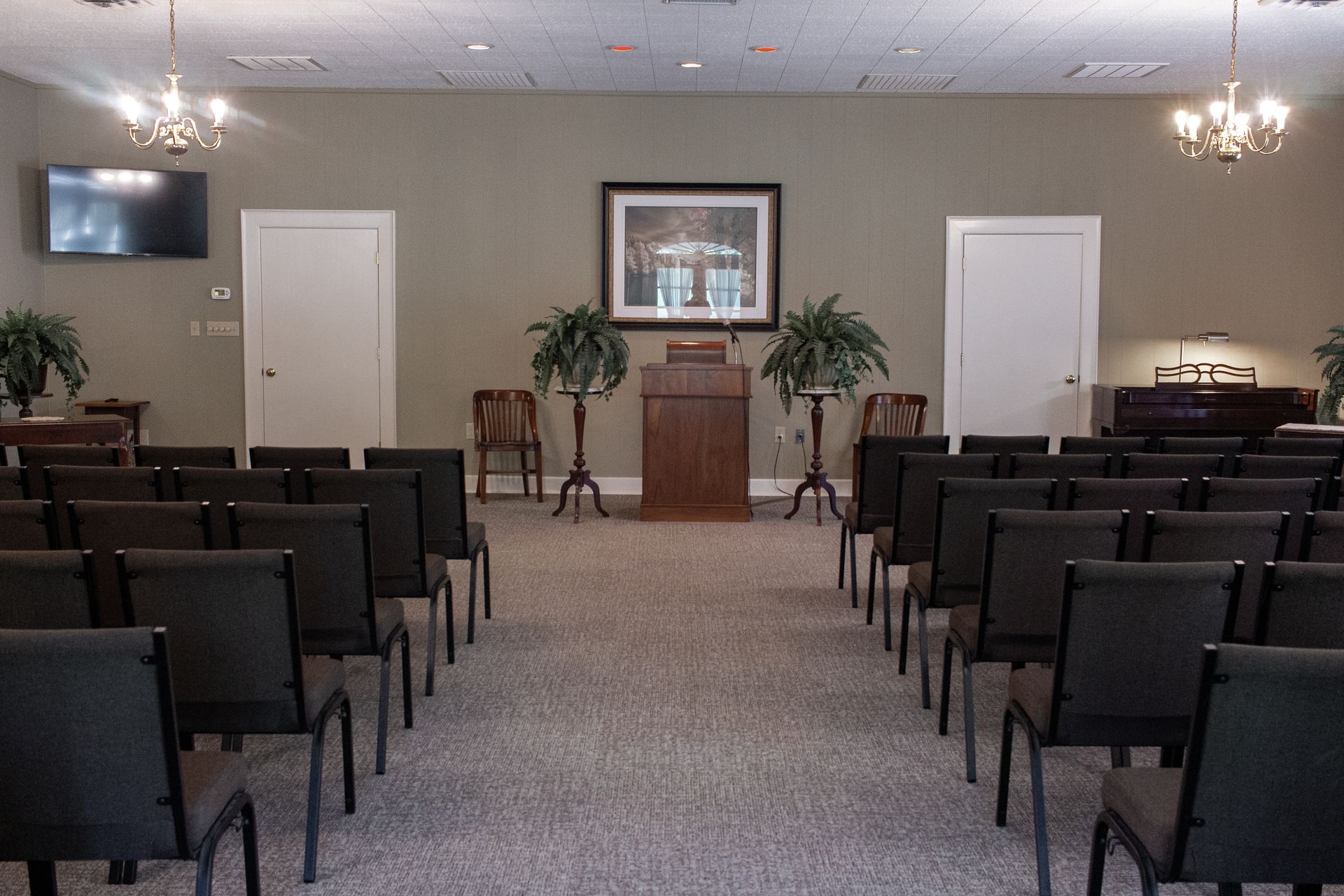 Empty chapel with rows of chairs facing a pulpit and framed cross at the front