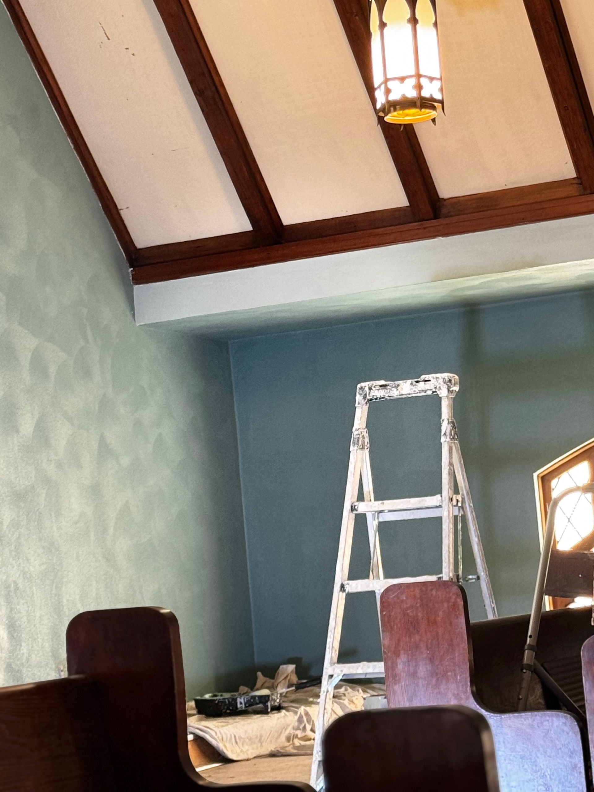 A beige, textured wall surface meeting a vertical edge, with a narrow sliver of light visible at the far left.