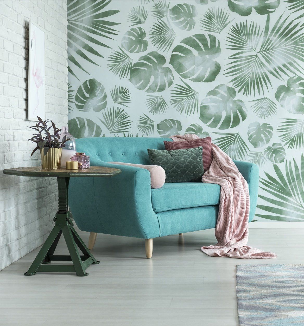 Picture of part of modern living room with a teal armchair and wooden side table in fornt of agreen leaf patterned designer wallpaper undertaken by painters and decorators London