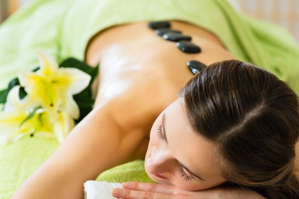 A Woman is Getting a Hot Stone Massage at a Spa — Nancy's Traditional Thai Massage In Buderim, QLD