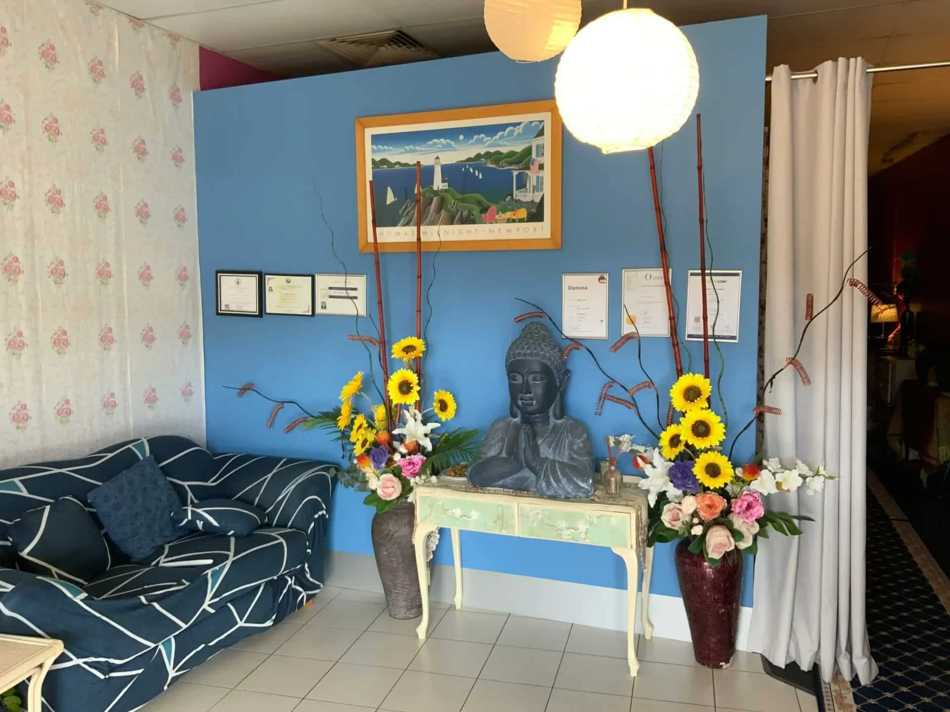 A Blue Wall Featuring Blooming Flowers and an Elegant Statue — Nancy's Traditional Thai Massage In Buderim, QLD