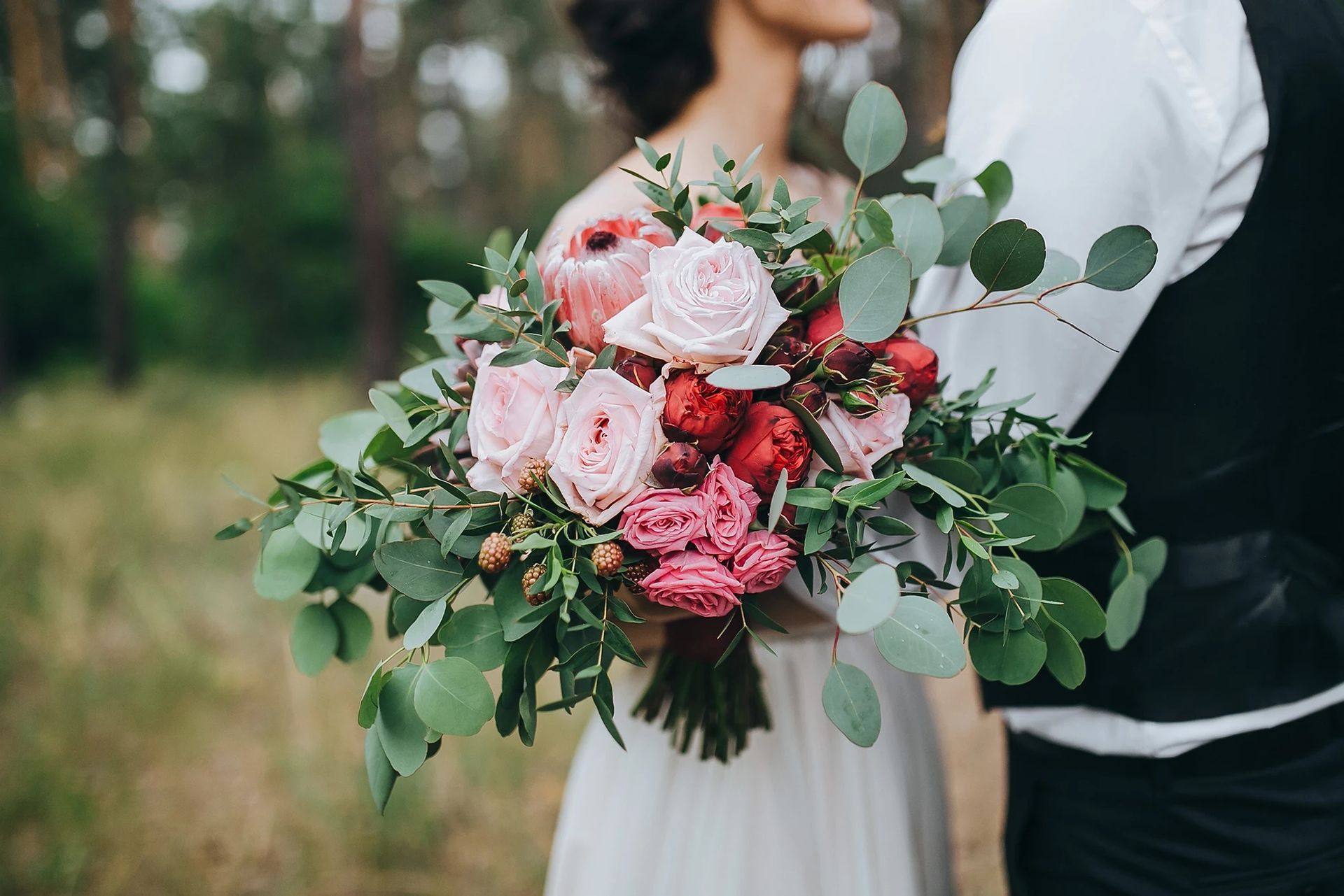 Une mariée et un marié tiennent un bouquet de fleurs.