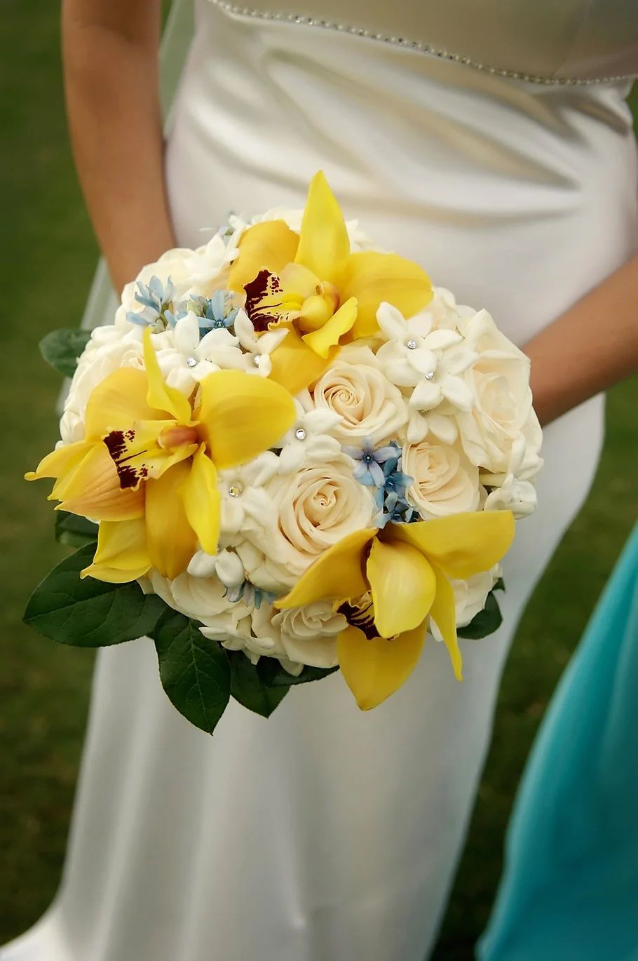 Une femme en robe blanche tient un bouquet de fleurs jaunes et blanches
