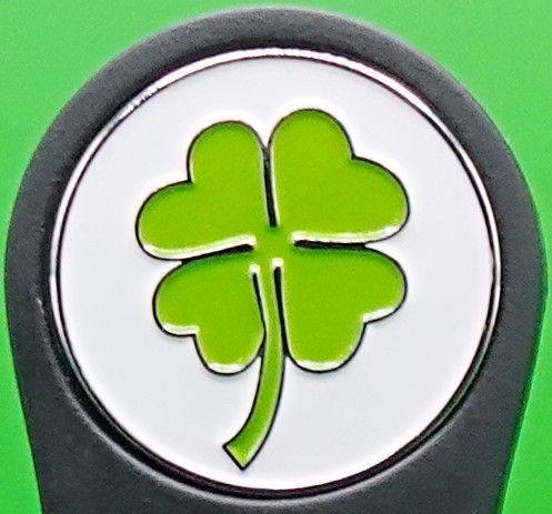 Green four-leaf clover symbol inside a white and silver circle, on a black background.