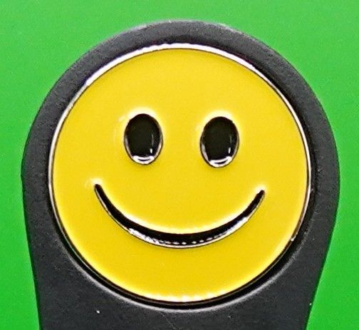 Yellow smiley face with black eyes and a curved mouth, set in a black frame, on a green background.