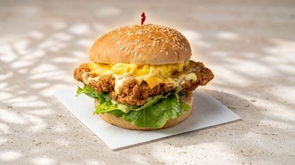 Close-up of a cheeseburger with lettuce and a sesame bun on a white napkin