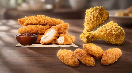 Assorted crispy fried chicken pieces and nuggets on a wooden table with dipping sauce