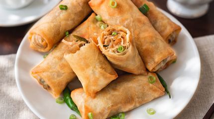 Plate of crispy golden spring rolls topped with chopped green onions