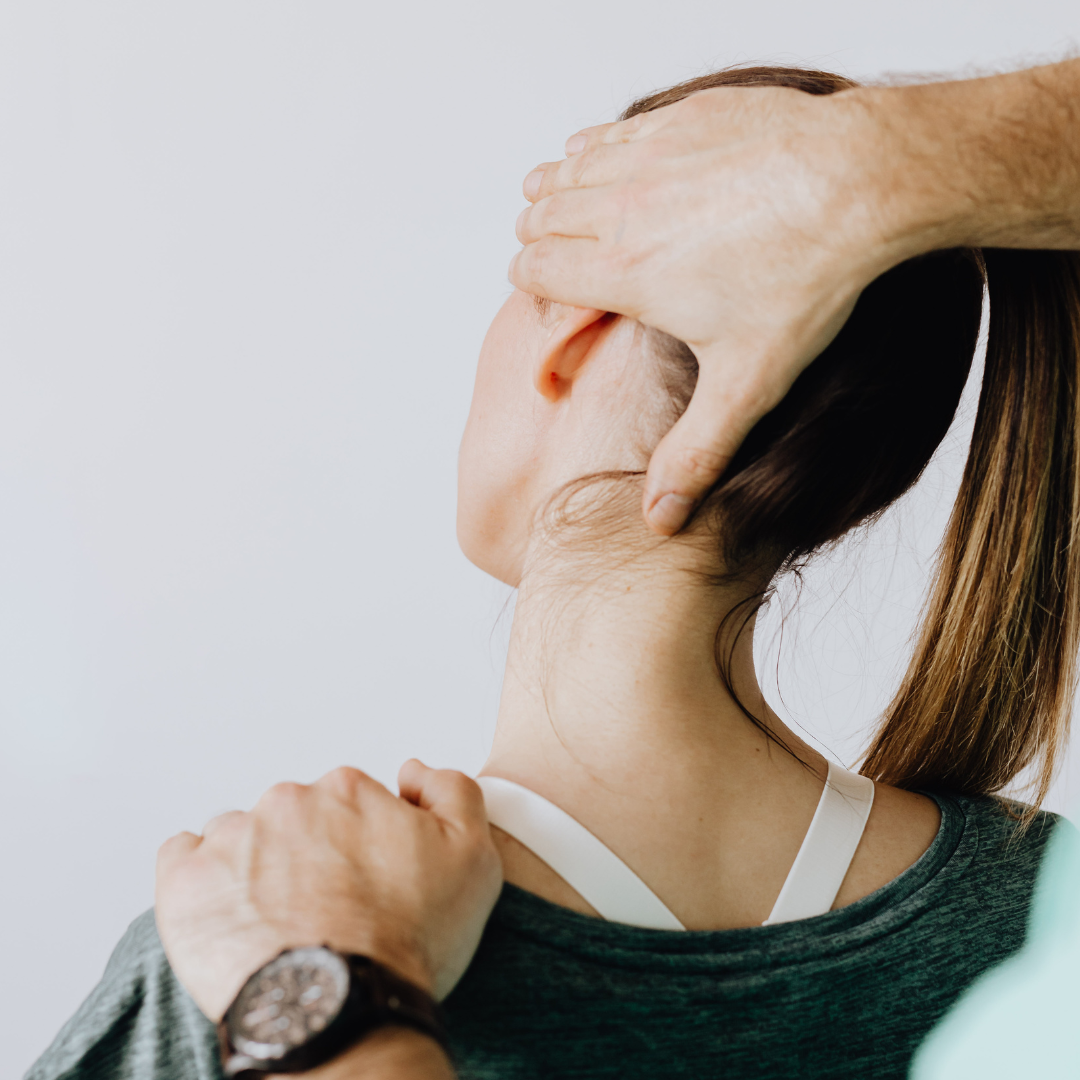 Person receiving neck adjustment from another person, hands on head and shoulder, white background.