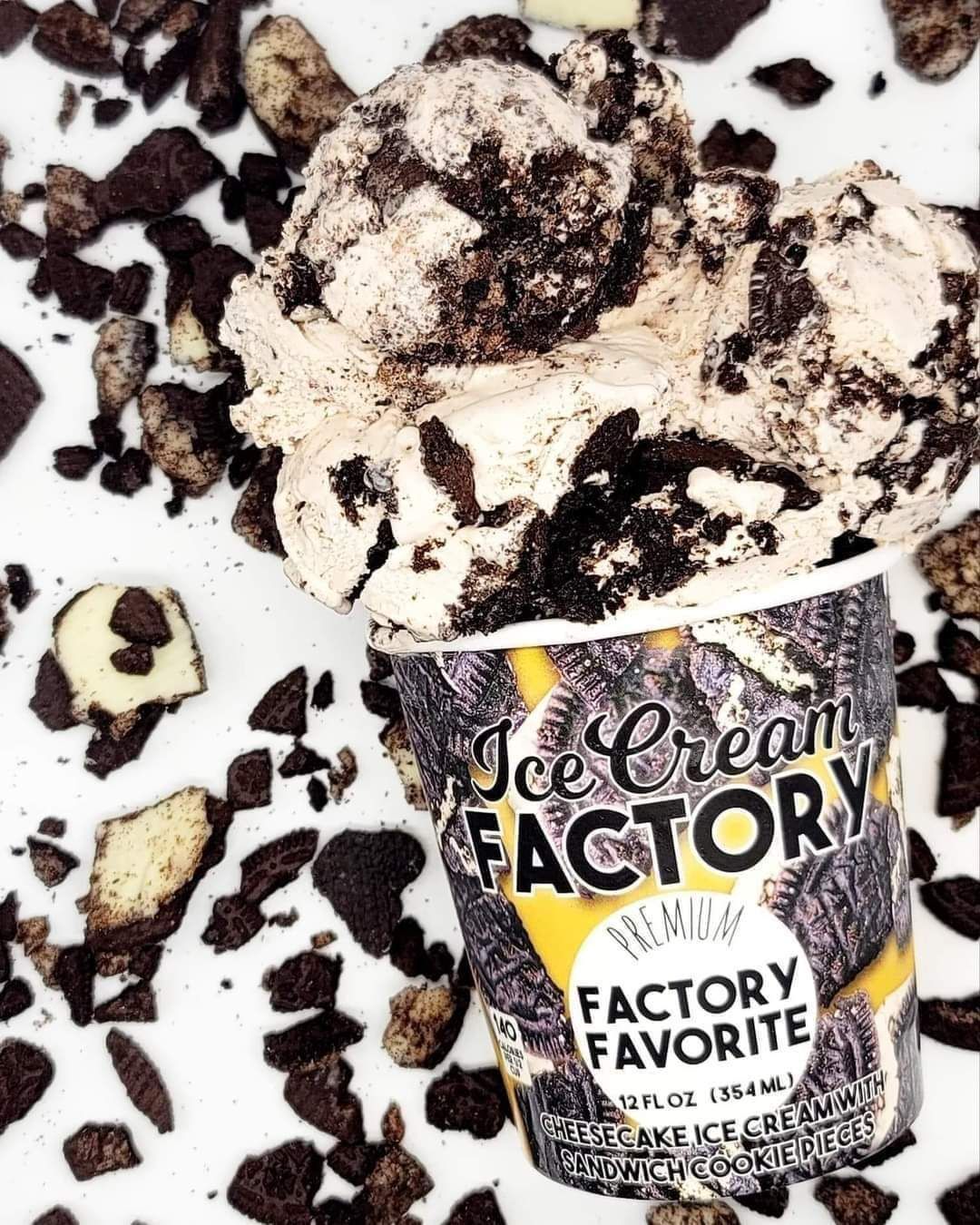 Ice cream tub labeled “Factory Favorite” with vanilla ice cream and dark cookie chunks scattered around it.