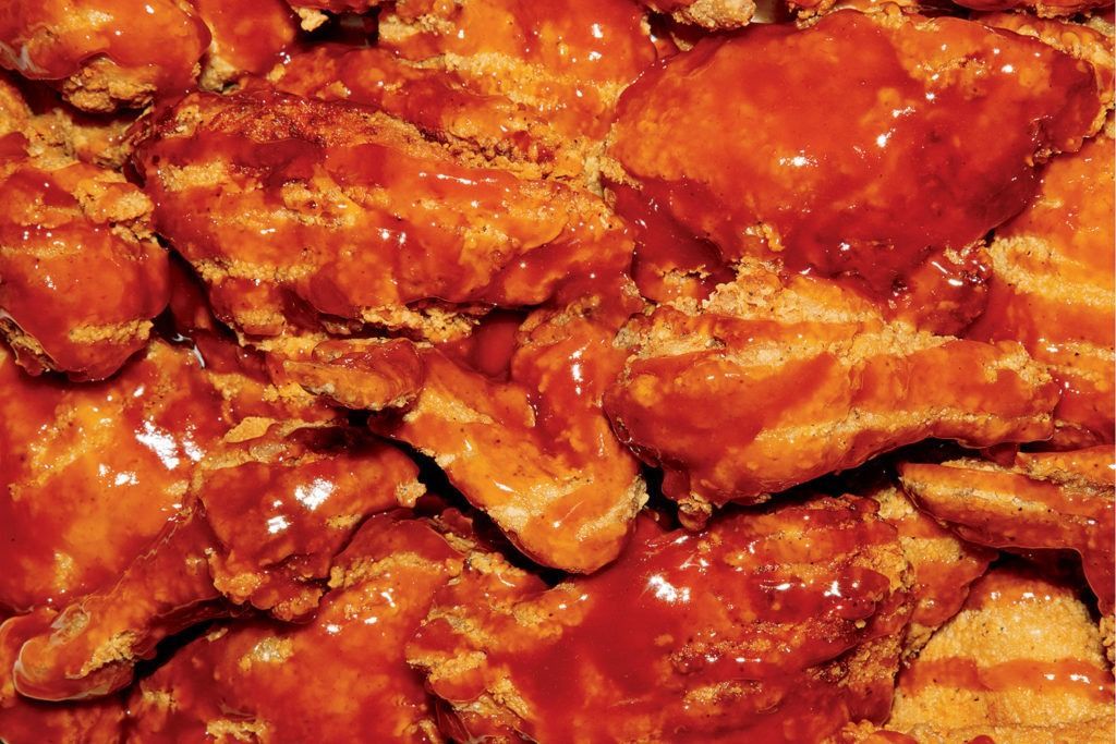 Close-up of saucy, glazed chicken wings in a rich red-orange coating