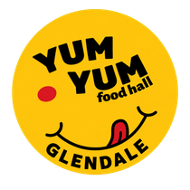 Yellow circular Yum Yum Food Hall Glendale logo with a smiling face and tongue out
