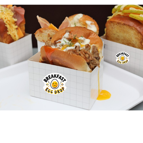 Breakfast sandwiches in white boxes on a white plate, with sunny-side-up egg and sauce spilling out.