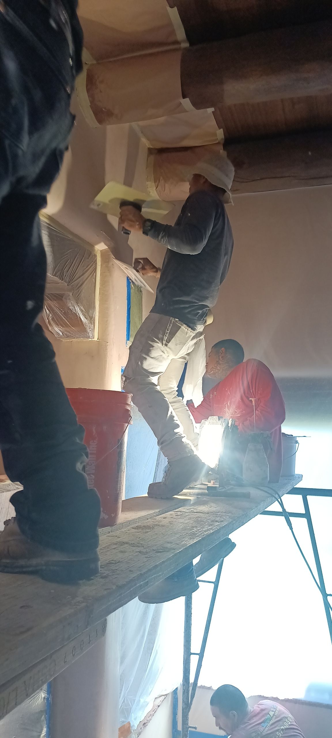 Workers on a scaffold repairing a ceiling opening inside a building under construction