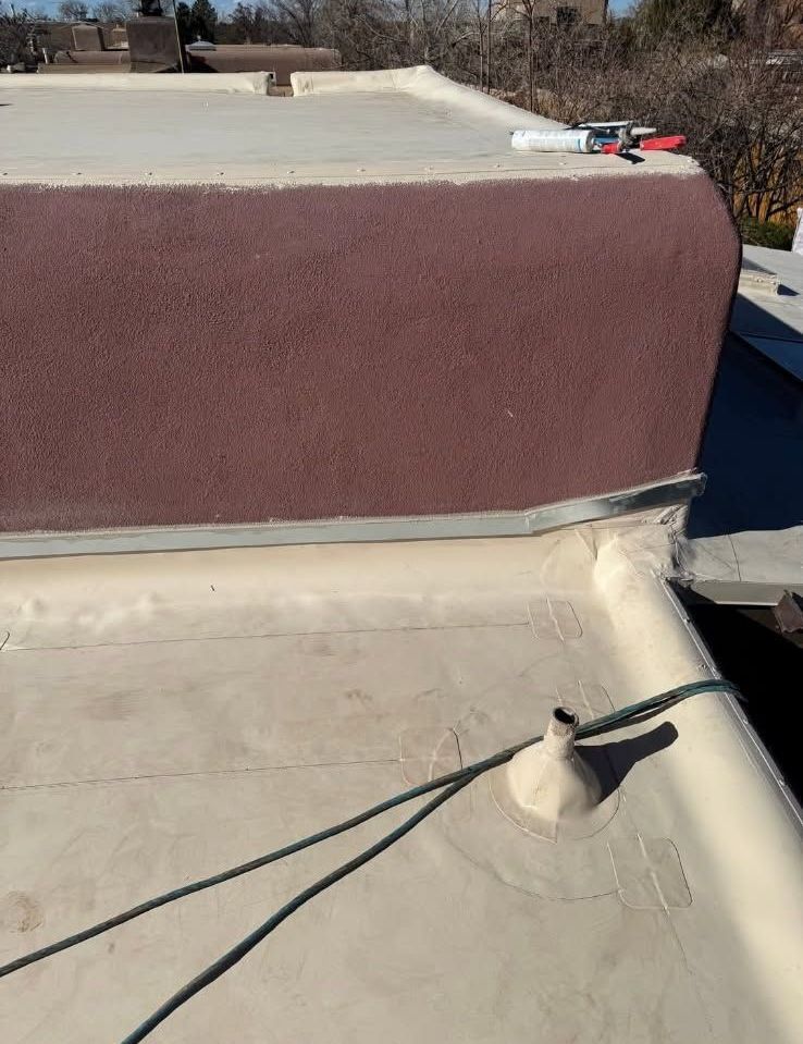 Rooftop with tan membrane, maroon parapet wall, and a black cable running across it
