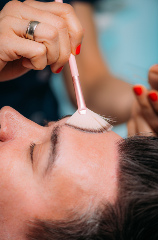 a woman is applying chemical peel to a man's face