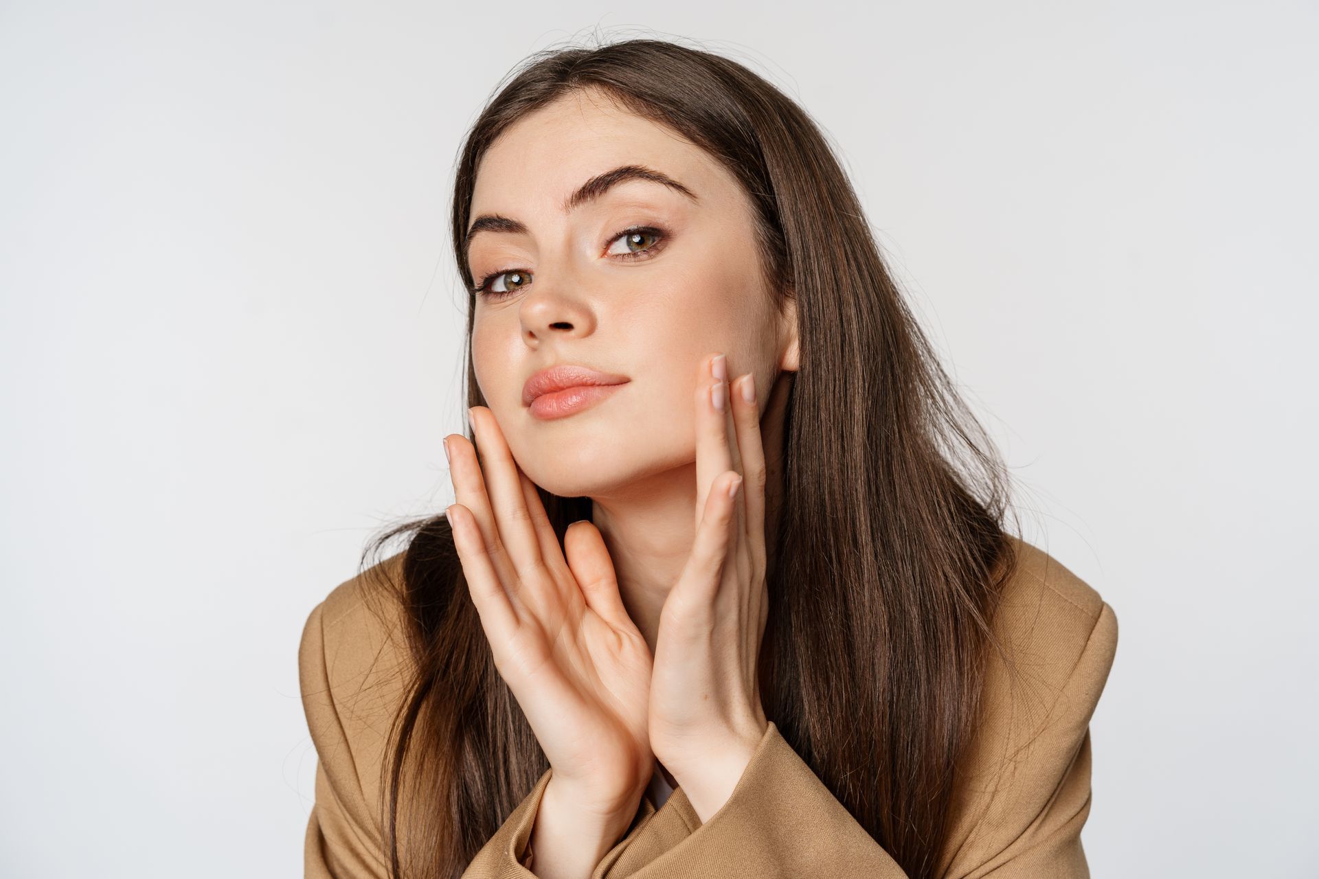 a woman in a brown jacket touches her face with her hands