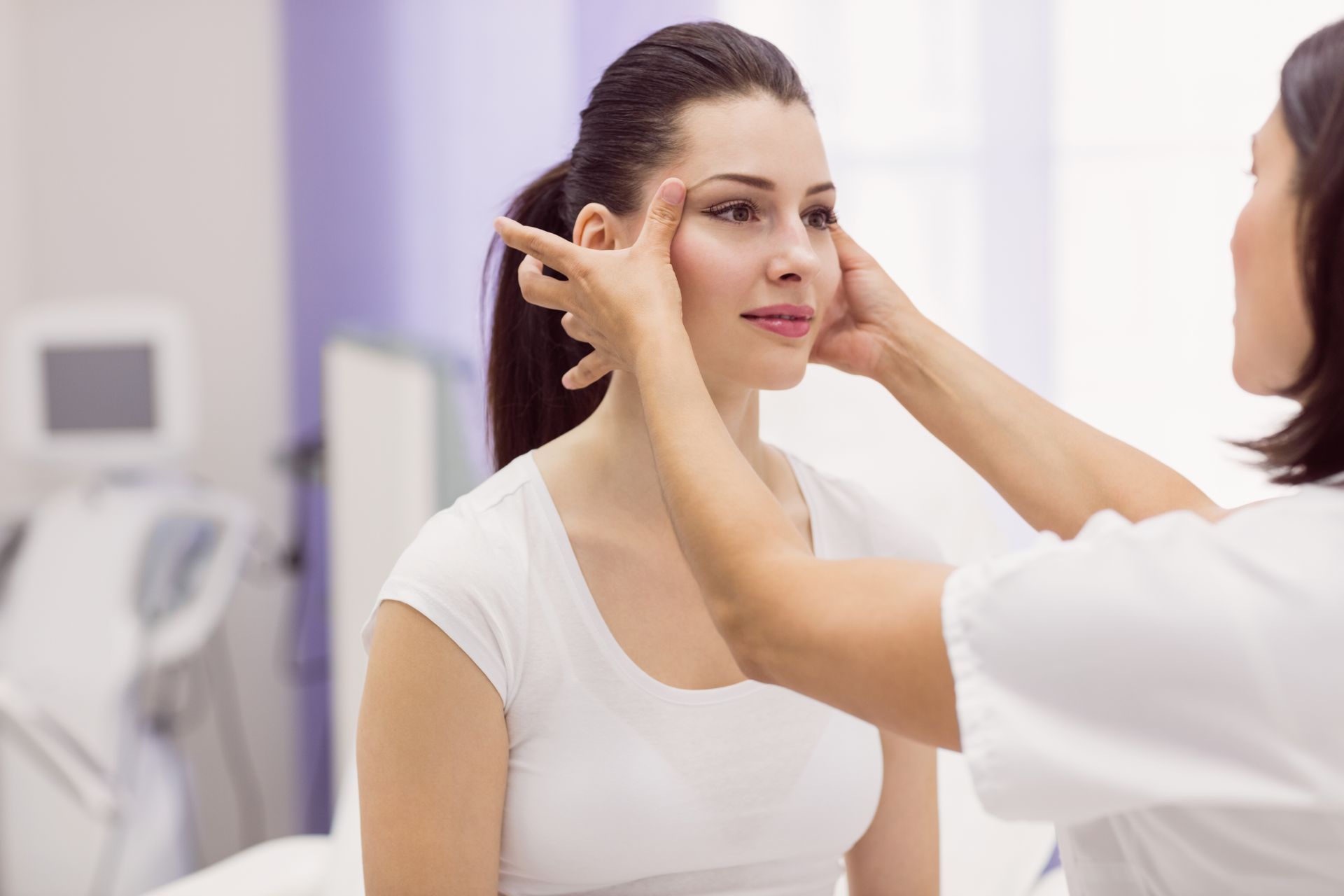 a woman is getting her face examined by a doctor