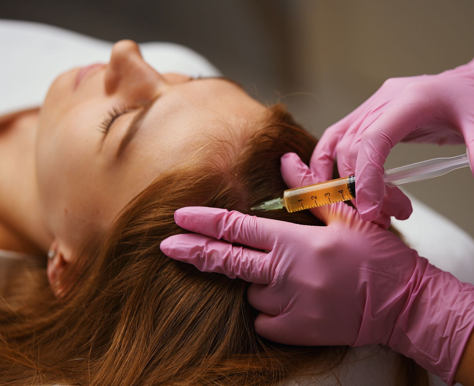 a woman in pink gloves is giving a prp injection