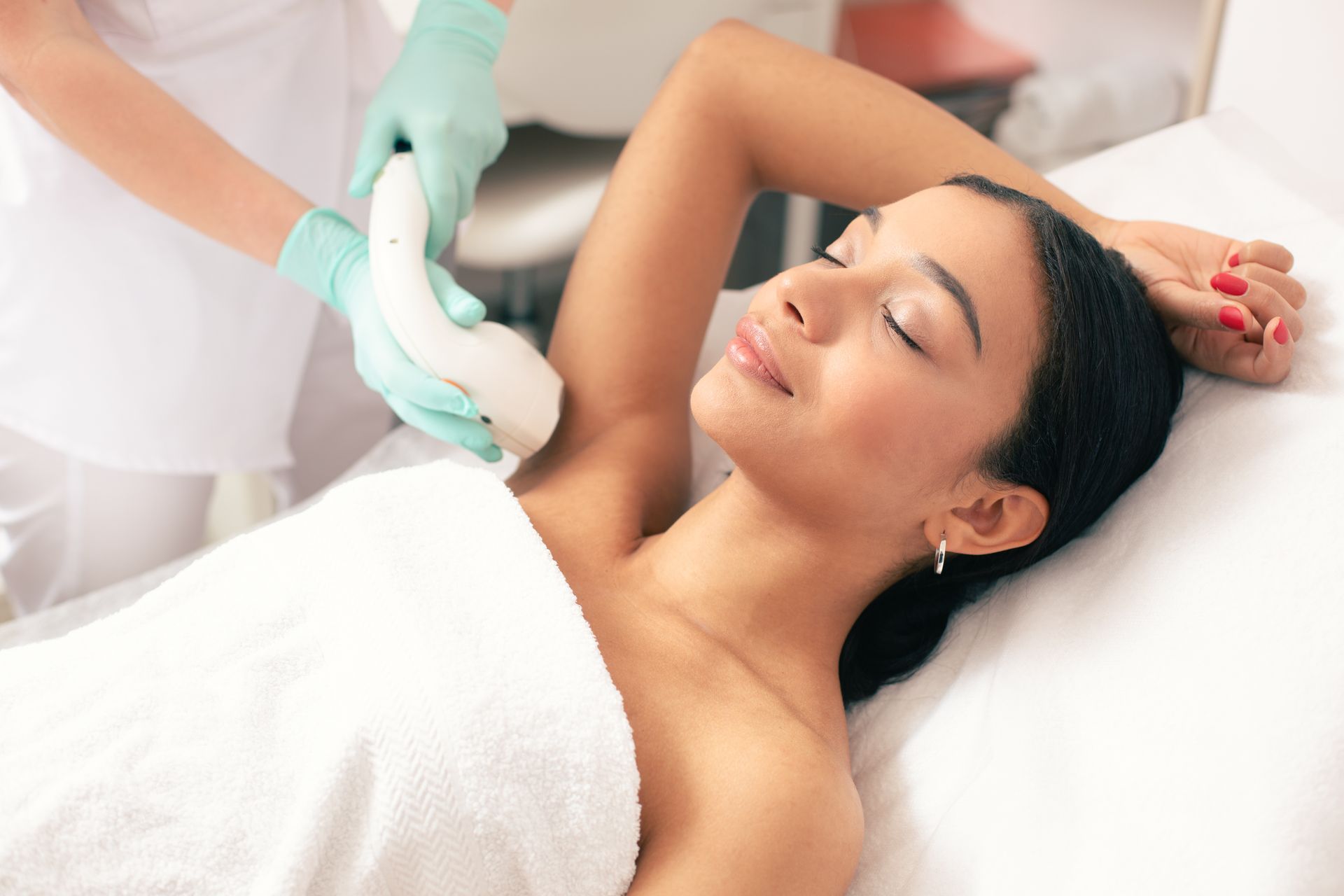 a woman is laying on a bed getting her armpit hair removed