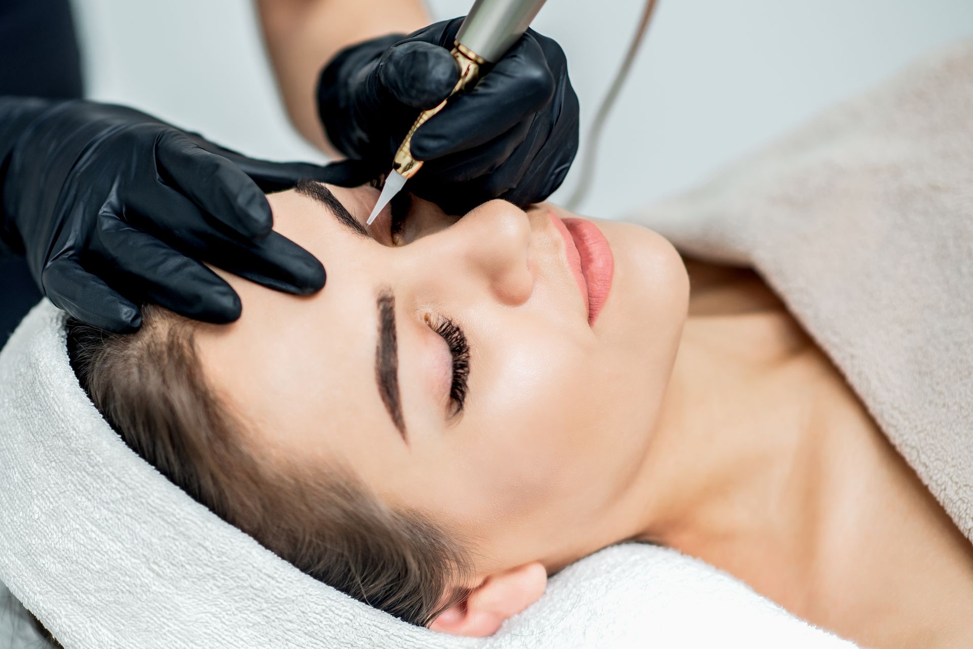 a woman is getting a tattoo on her eyebrows