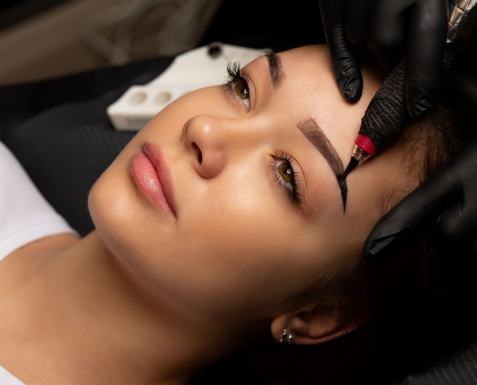 a woman is getting a tattoo on her eyebrows