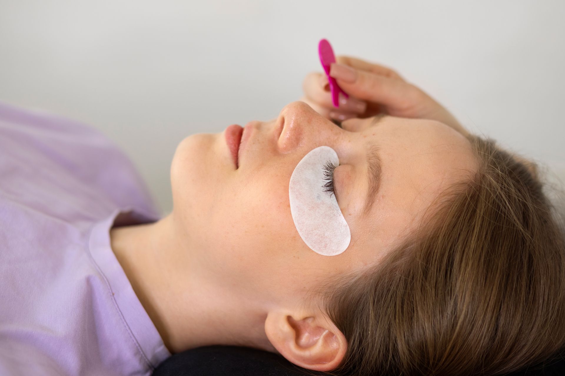 a woman with a pink tweezer on her eye