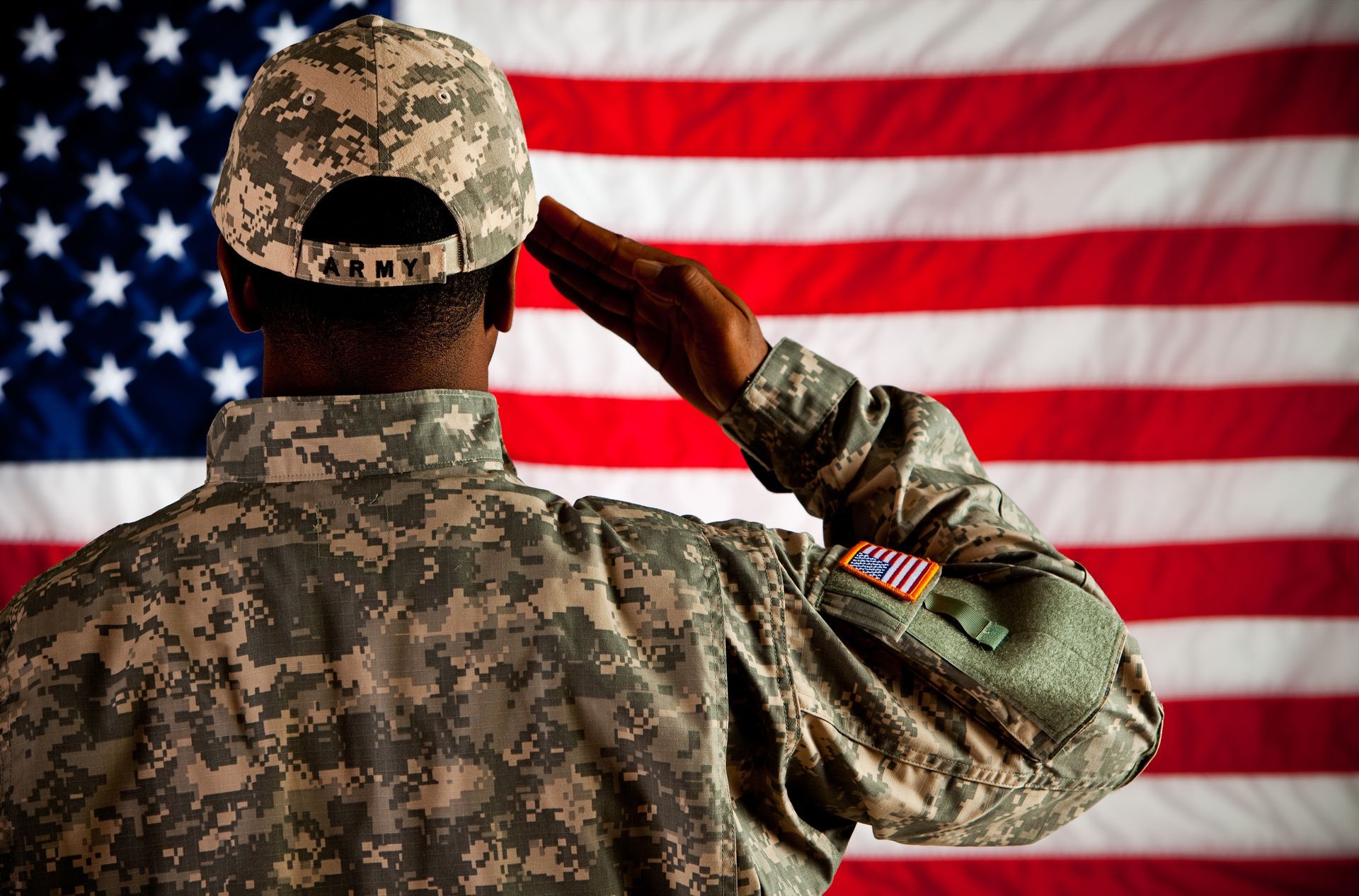 A man in a military uniform is holding an American flag in his hands.