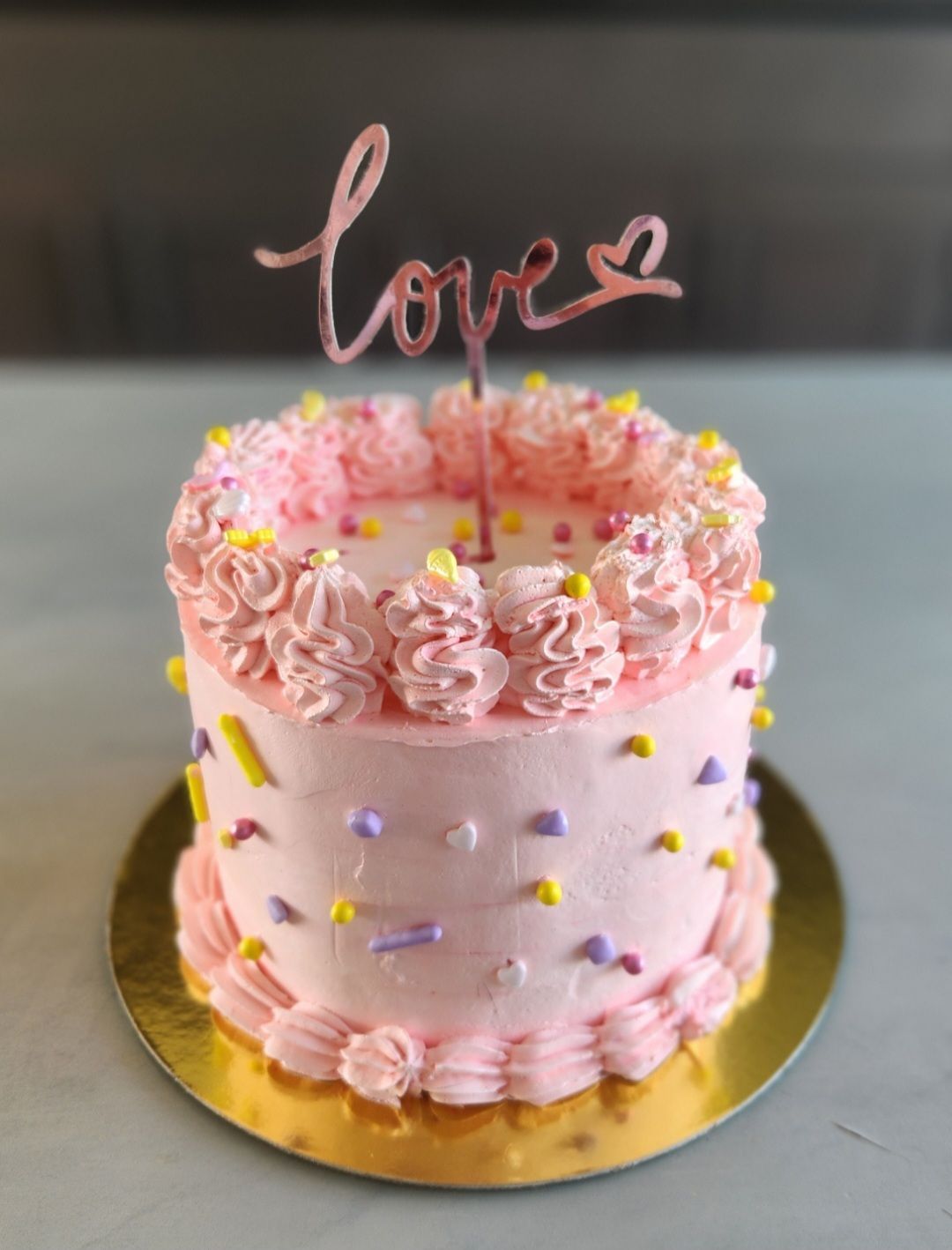Un pastel rosa con un adorno que dice amor.