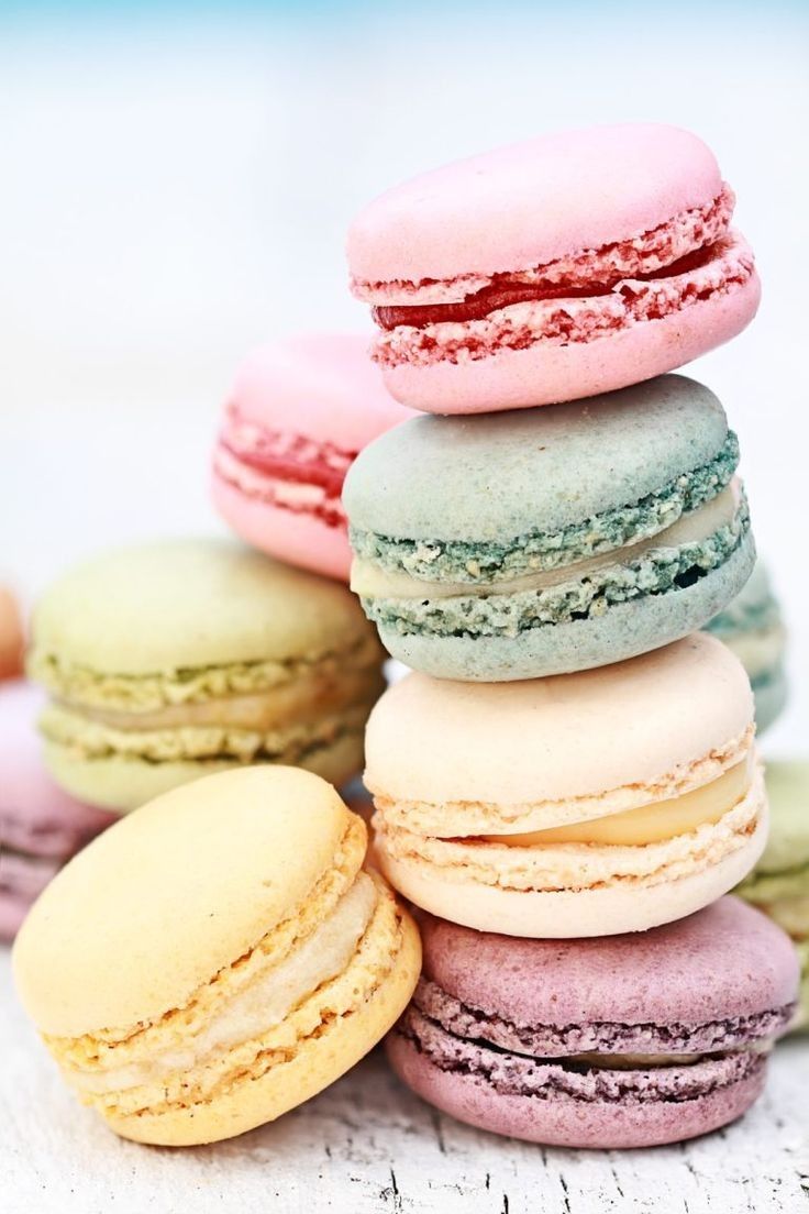 Un montón de macarons coloridos se apilan uno encima del otro en cajas.