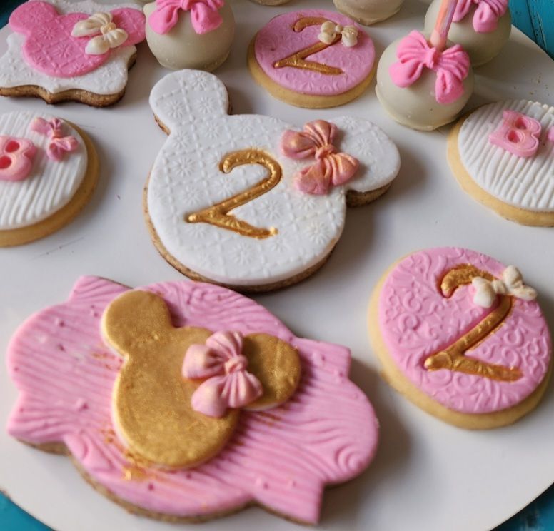 Un plato de galletas rosas y blancas con el número 2 en ellas.