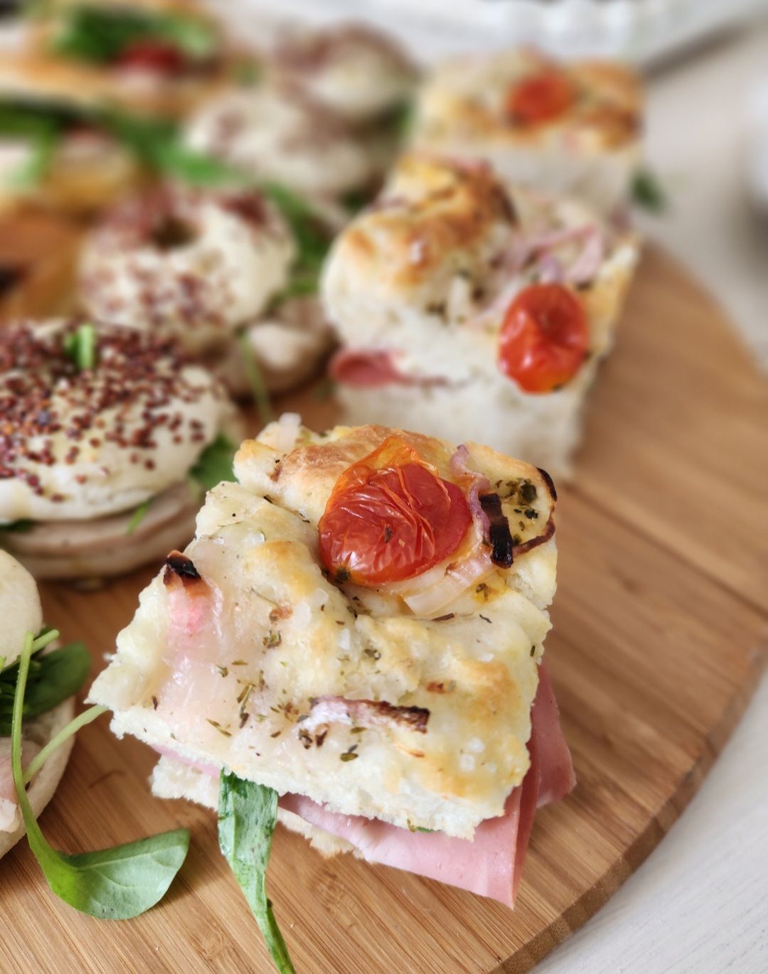 Surtido de aperitivos: sándwiches, bagels, mini quiches y frituras en platos y en caja.