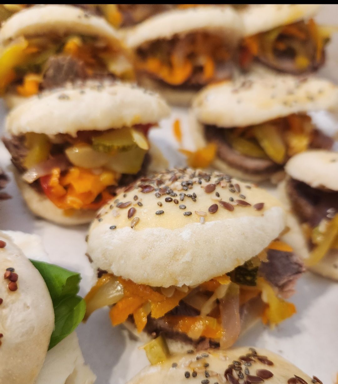 Un montón de sándwiches con semillas de sésamo encima.
