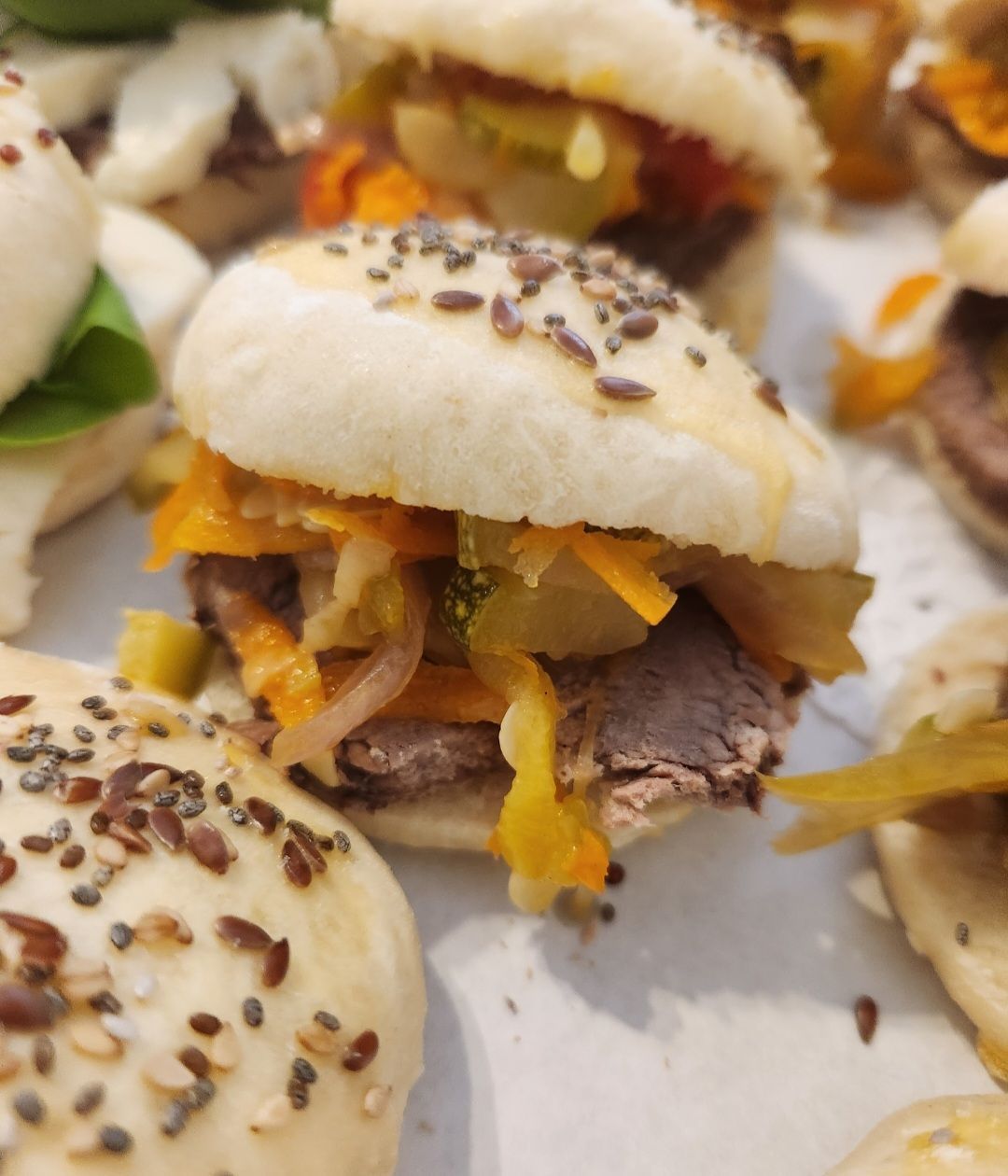 Un montón de sándwiches con semillas de sésamo encima.