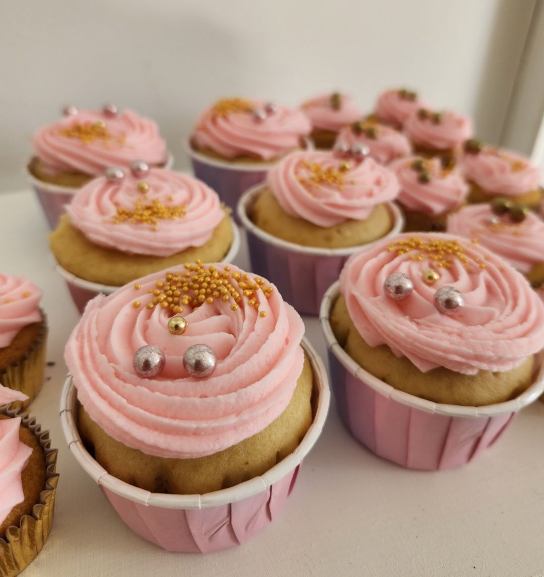 Un montón de cupcakes con glaseado rosa y chispas.