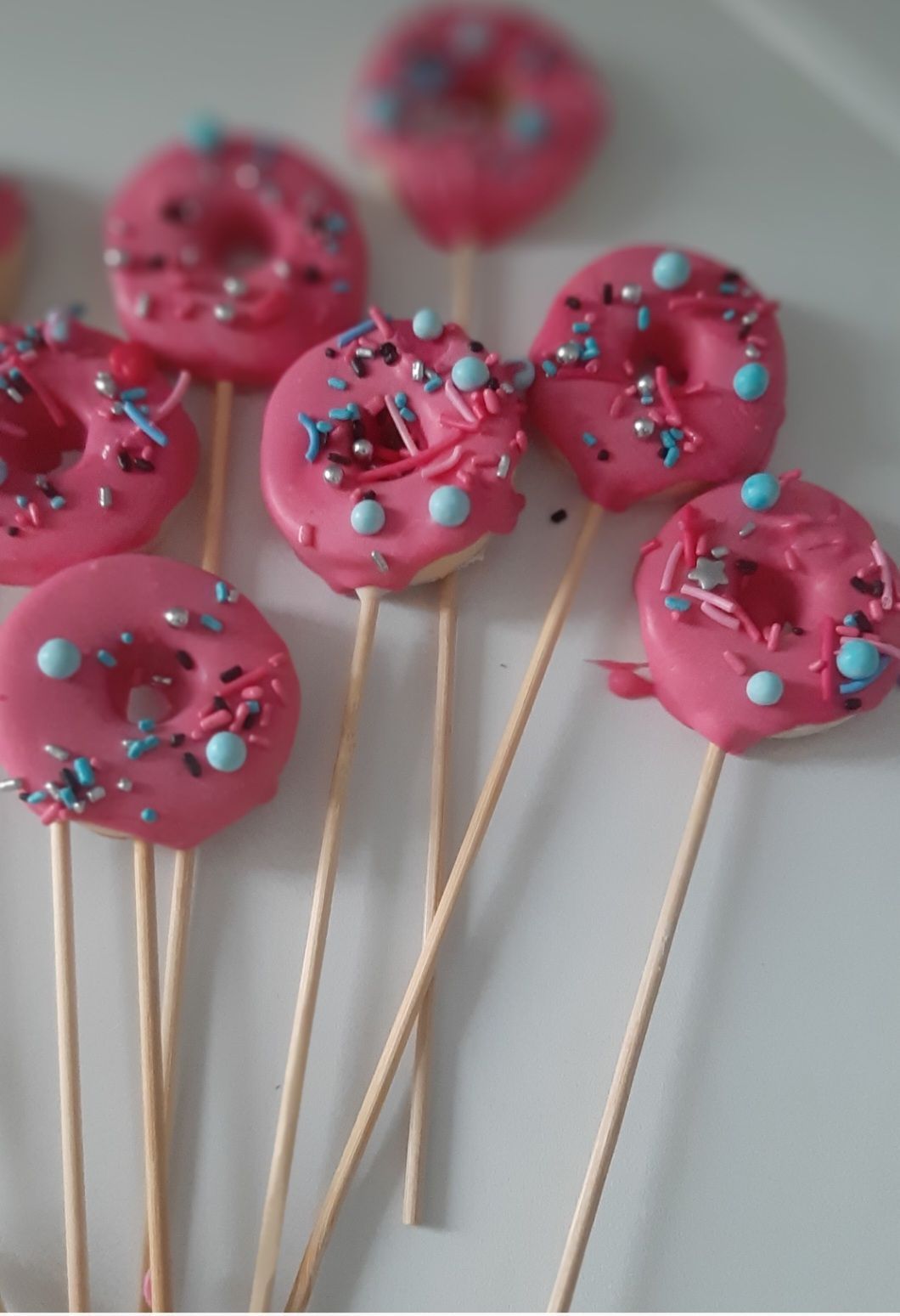 Paletas de donut rosa con chispas en palitos de madera.