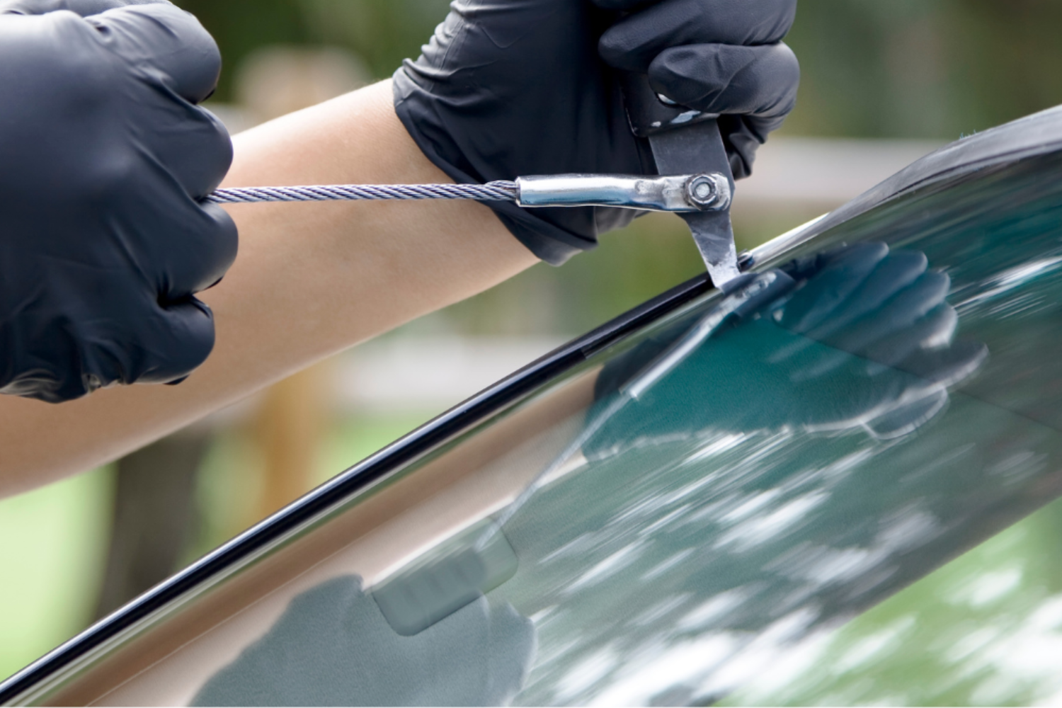 Gloved hands using a windshield tool to remove a car windshield wiper arm.