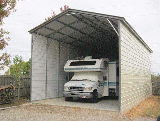 White camper truck parked inside a large metal carport with an open front.