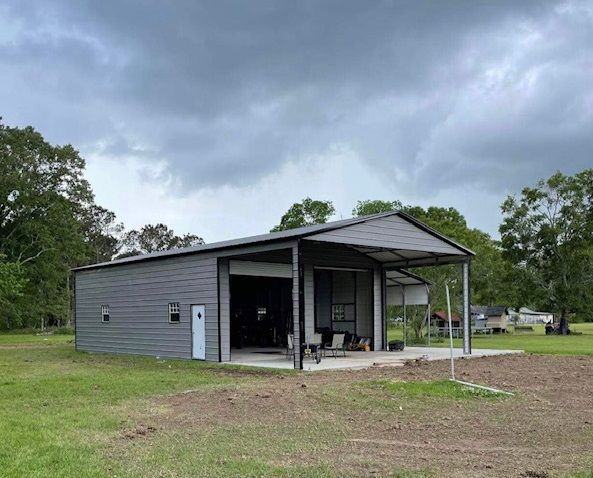 Gray metal shed with open bays in a grassy yard under a cloudy sky
