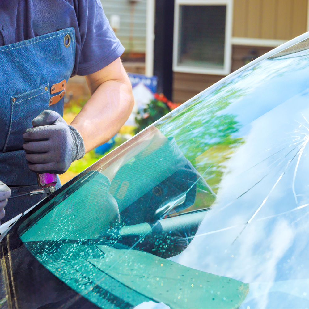 Mechanic wiping a car windshield with a squeegee