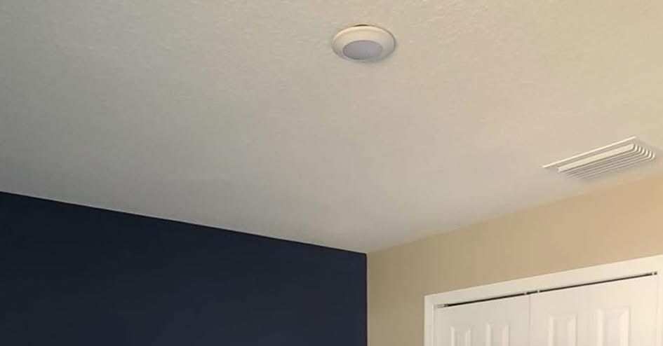 White ceiling with recessed light, blue and tan walls, and white door.