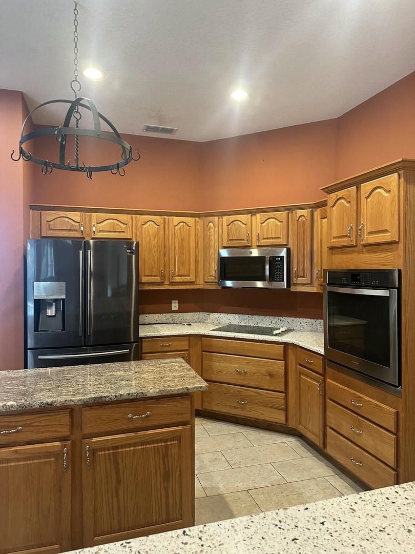 Kitchen with wooden cabinets, granite countertops, and stainless steel appliances.