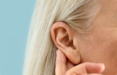 A woman is touching her ear with her hand.