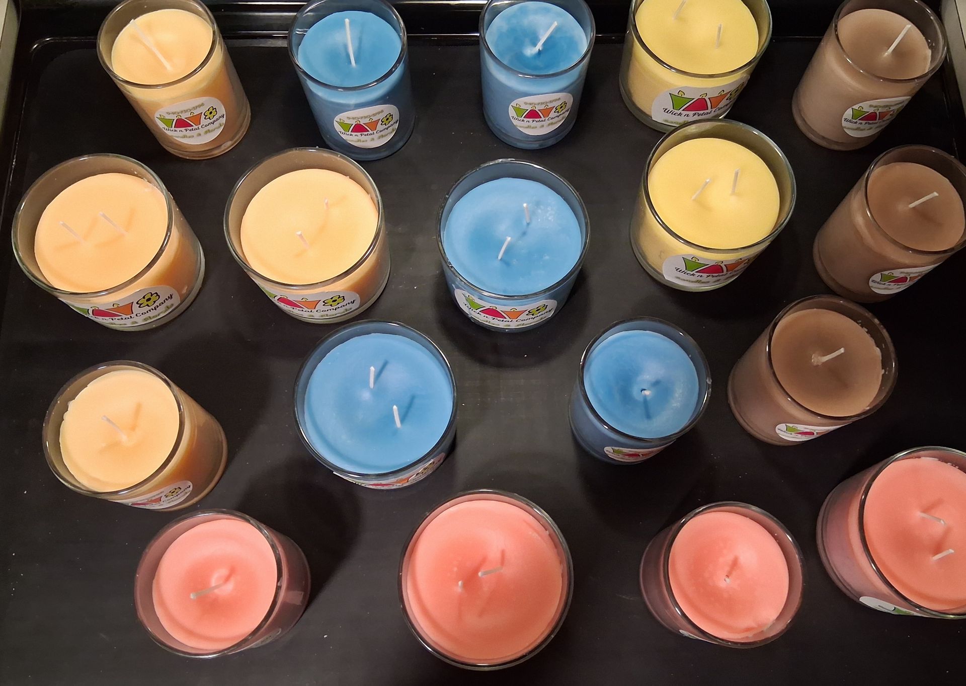 Assorted colored candles arranged in rows on a black surface