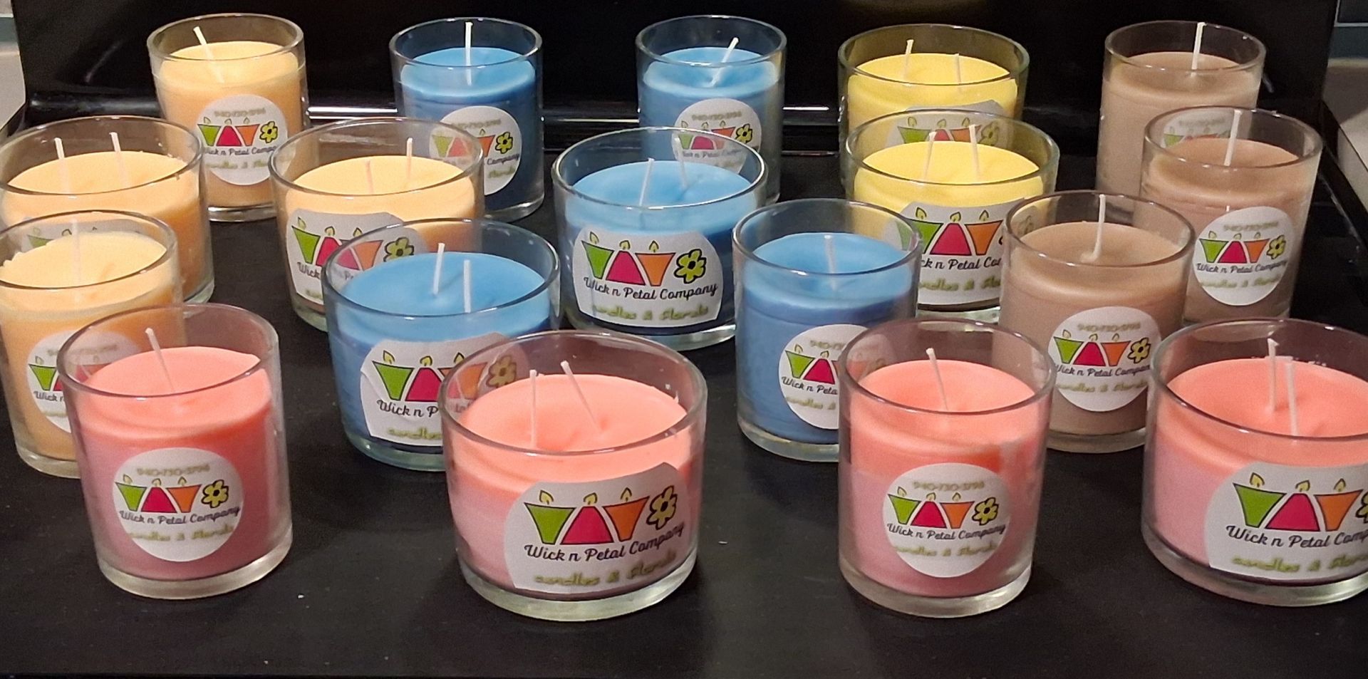 Assorted colorful scented candles arranged on a table in clear glass jars