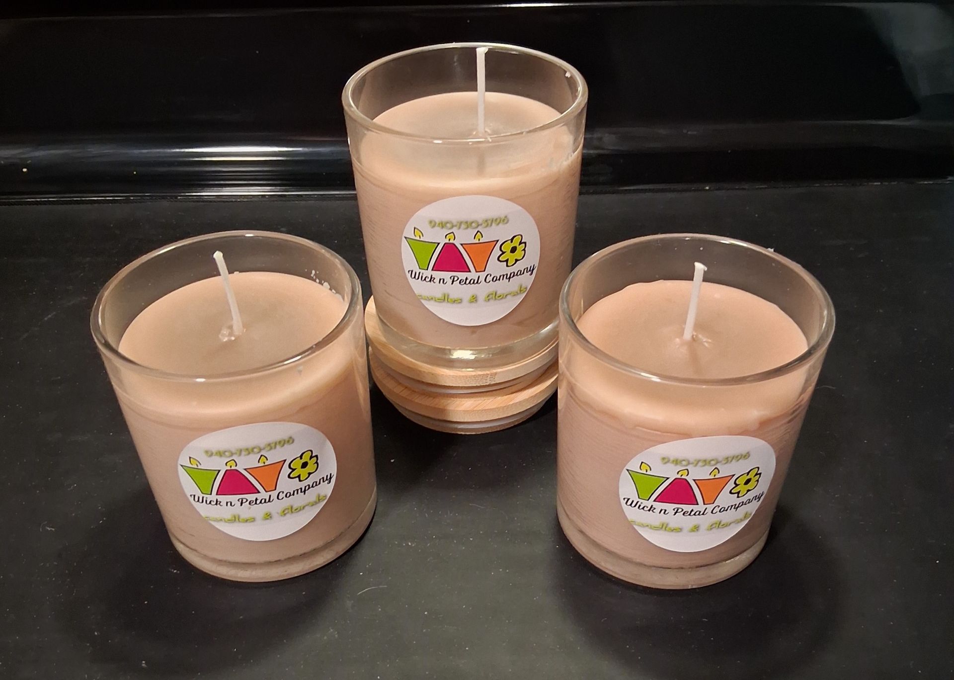 Three peach-colored candles with labels arranged on a black surface.