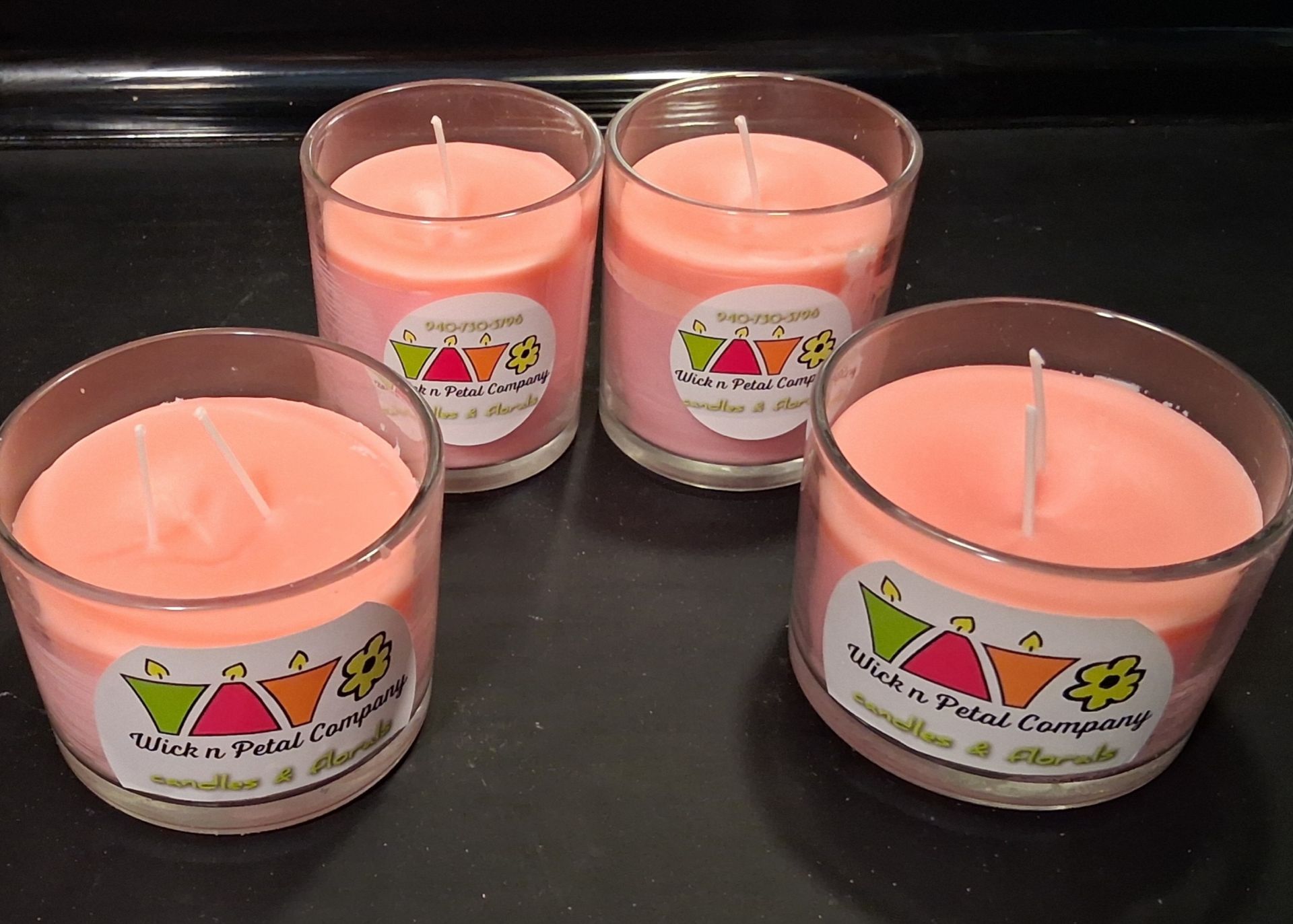 Four pink candles in clear glass holders on a dark surface