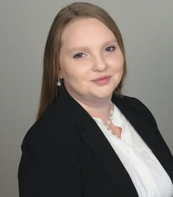 A woman wearing a black jacket and a white shirt is smiling for the camera.