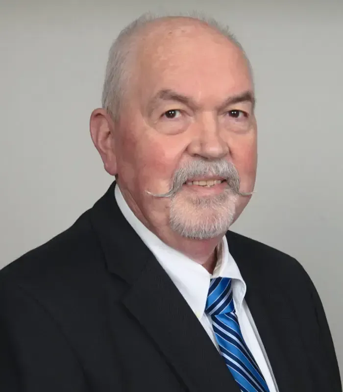 A man with a beard and mustache is wearing a suit and tie.