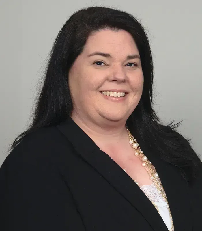 A woman in a black jacket and white shirt is smiling for the camera.